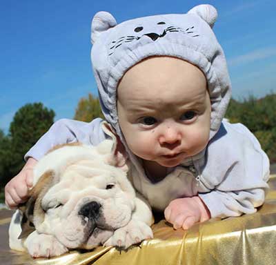 Infant hugging english bulldog puppy